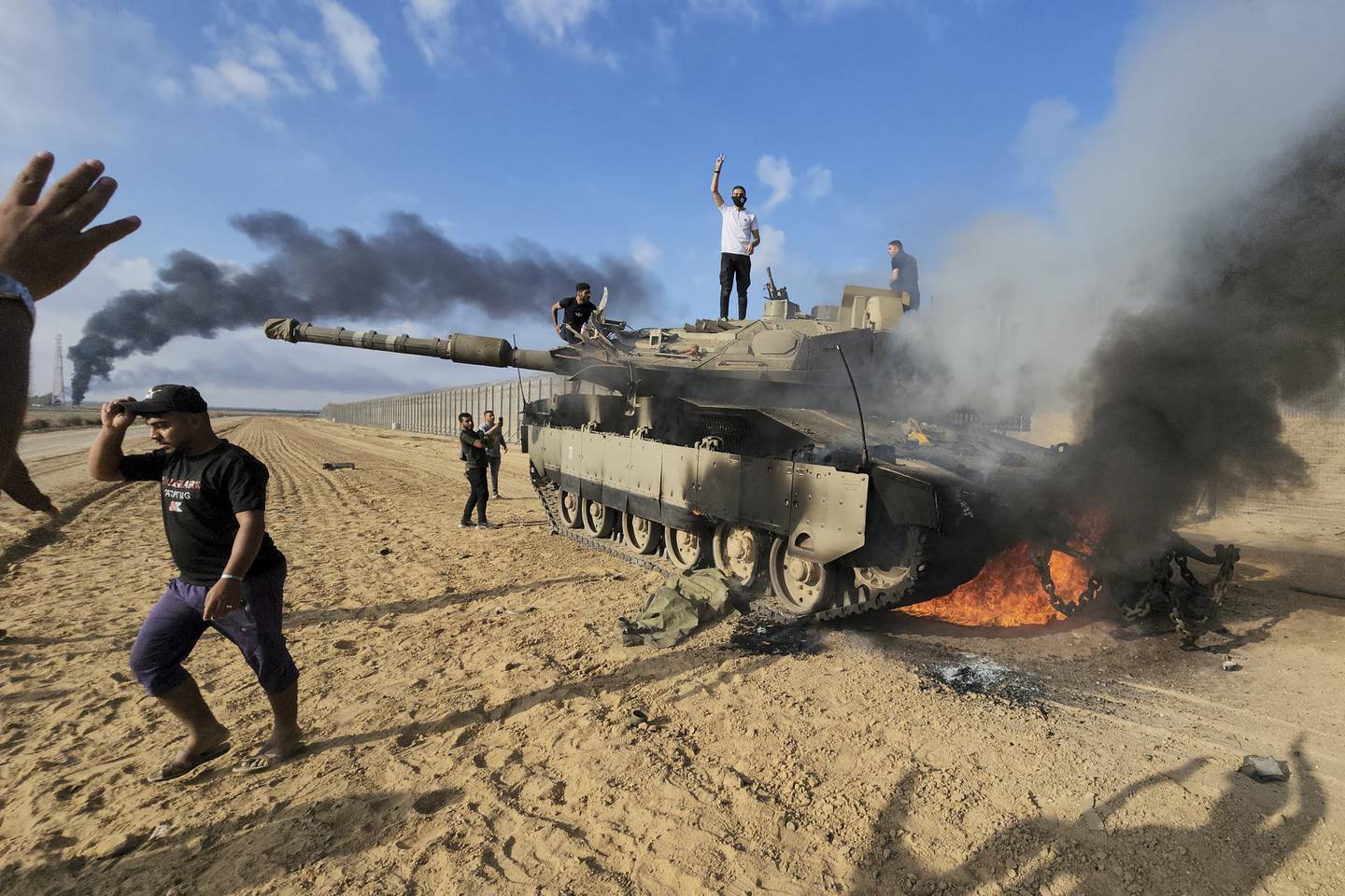 Palestinere feirer ved en ødelagt israelsk stridsvogn på Gazastripen, ved grensegjerdet øst for Khan Younis lørdag. Foto: Hassan Eslaiah / AP / NTB