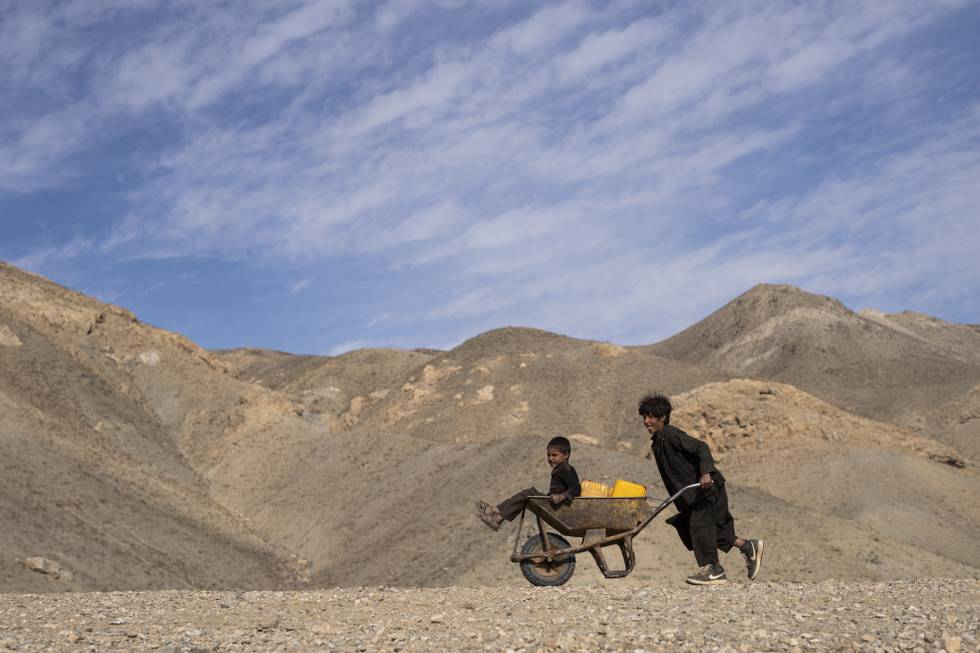En gutt triller lillebroren sin i en trillebår. De to er på vei for å hente vann om lag 3 kilometer fra der de bor utenfor Herat vest i Afghanistan. Landet er rammet av tørke og matmangel, og FN frykter en større sultkatastrofe. Foto: Petros Giannakouris / AP / NTB