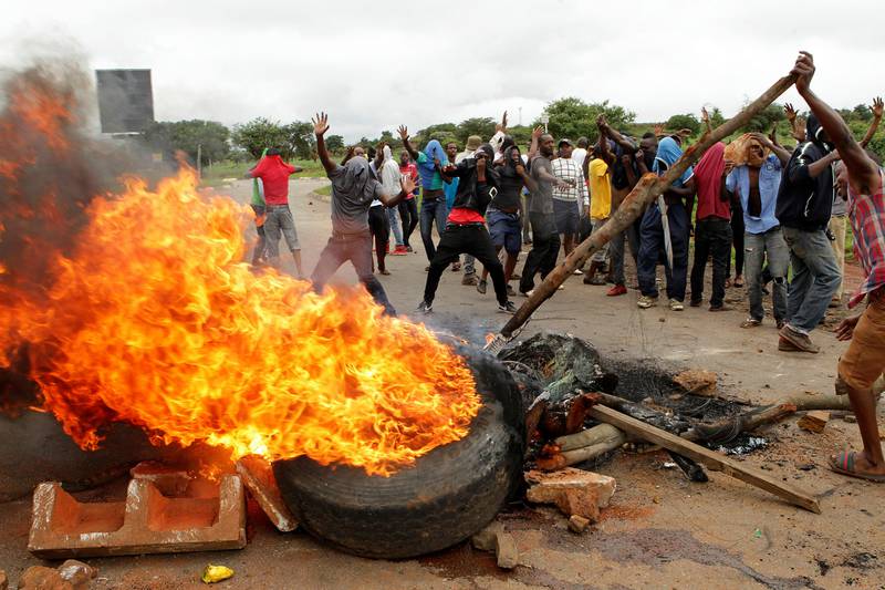 FILE - In this Tuesday, Jan. 15, 2019 file photo, protestors gather near a burning tire during a demonstration over the hike in fuel prices in Harare, Zimbabwe. 2019 is already a busy year for internet shutdowns in Africa, with governments ordering cutoffs as soon as a crisis appears. Zimbabwe ordered a Äútotal internet shutdownÄù in recent days during protests over a dramatic fuel price increase and a resulting deadly crackdown. (AP Photo/Tsvangirayi Mukwazhi, File)
