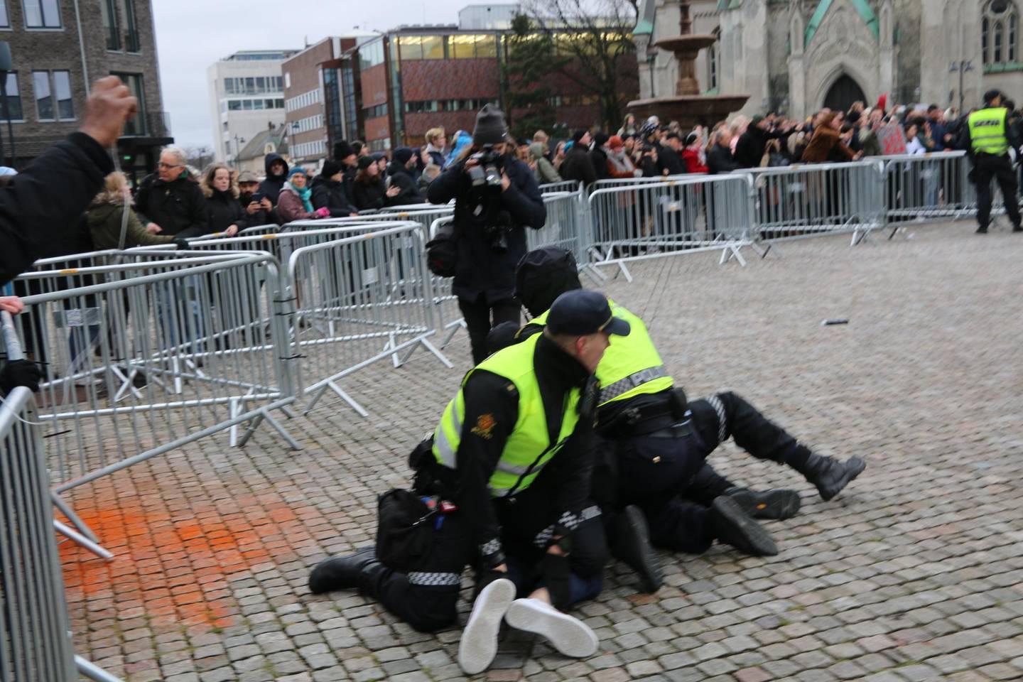 Politimenn legger en motdemonstrant i bakken.