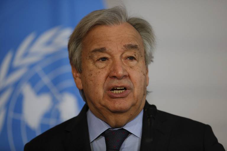 Bildet er av FNs generalsekretær António Guterres. Han har på dress. Det er et blått FN-flagg i bakgrunnen. Det er et hvitt omriss av verdens kontinenter på flagget. De er omgitt av en laurbærkrans. Foto: Theresa Wey / AP / NTB
