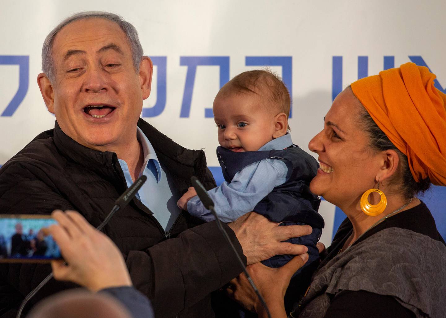 Israeli Prime Minister Benjamin Netanyahu is introduced to a baby named after him after planting a tree during an event on the Jewish holiday of Tu' BiShvat in the Jewish settlement of Mevo'ot Yericho, in the Jordan Valley near the Palestinians city of Jericho, Monday, Feb. 10, 2020. (AP Photo/Ariel Schalit)