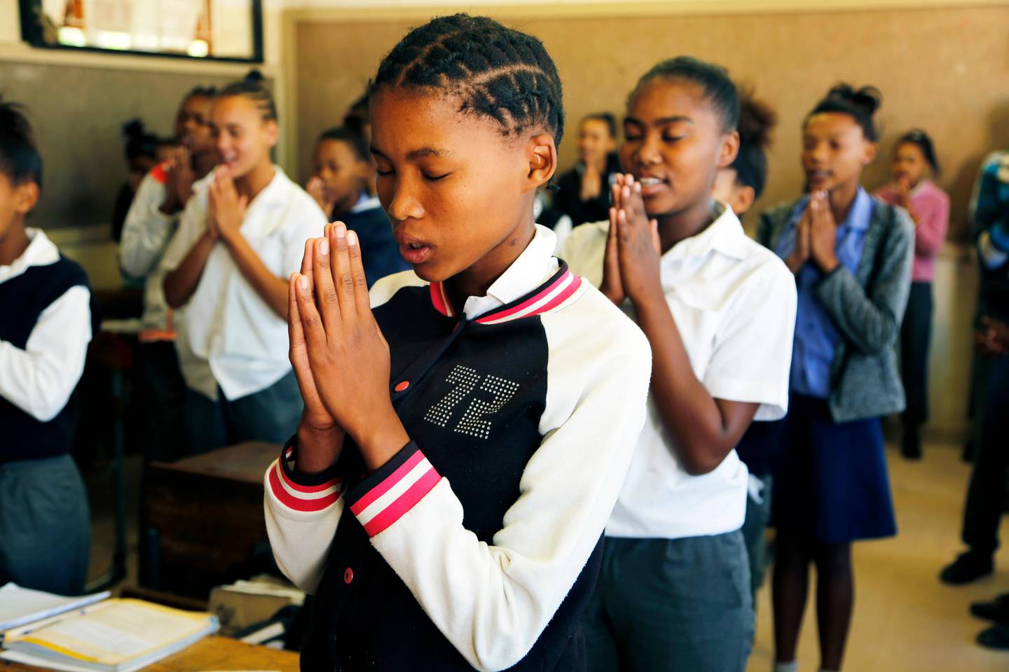 In this photo taken on Thursday, Nov. 14, 2019, children say grace before receiving their food which they are about to receive at the Delta Primary School in Vosburg, South Africa. The worst drought some farmers have seen in decades is affecting much of southern Africa. The United Nations says more than 11 million people now face crisis levels of food insecurity. (AP Photo/Denis Farrell)
