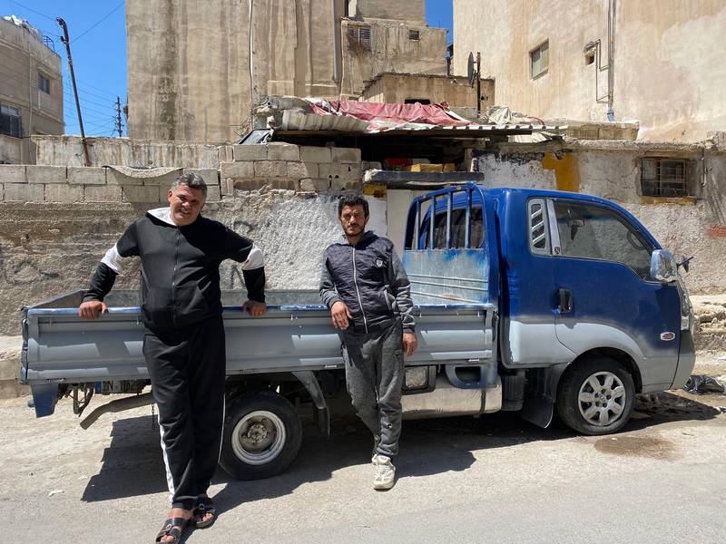 In this April 13, 2020, photo, brothers Mohammed and Khalil Yousef pose in front of a pickup truck in the Palestinian refugee camp of al-Wehdat in Jordan’s capital of Amman. The brothers used to make a living as drivers working day to day, but work has stopped since Jordan ordered a nationwide lockdown to halt the spread of the coronavirus. (AP Photo/Omar Akour)