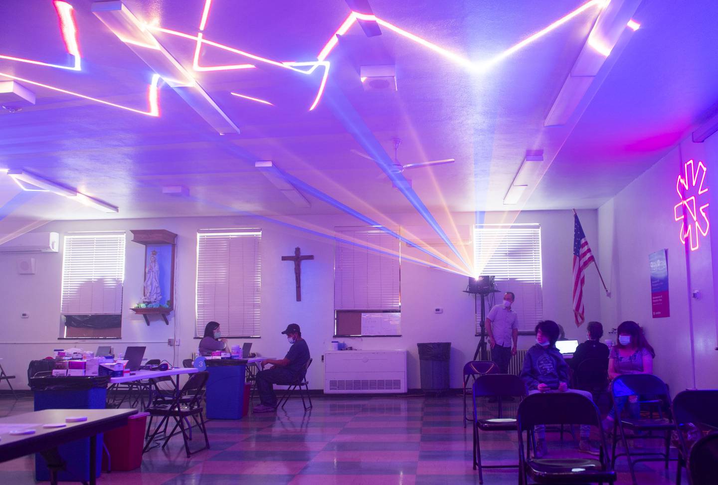 People sit and wait, Monday, May 17, 2021, at a COVID-19 vaccination clinic at St. Patrick Catholic Church in Canonsburg, Pa., which featured laser beams and music. George Dodworth, of Lightwave International, helped set up the vaccination site and decided to add lasers and music to try to make it more fun and ease some of the apprehension and anxiety younger groups might feel while getting the vaccine. (Emily Matthews/Pittsburgh Post-Gazette via AP)