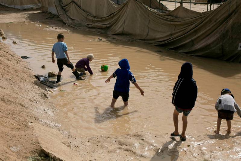 FILE - In this March 31, 2019 file photo, children play in a mud puddle in the section for foreign families at Al-Hol camp in Hasakeh province, Syria. A Syrian Kurdish official said Monday, June 10, 2019, that authorities in northeastern Syria have handed 12 French and two Dutch orphans whose fathers were killed fighting for the Islamic State group back to their countries. (AP Photo/Maya Alleruzzo, File)