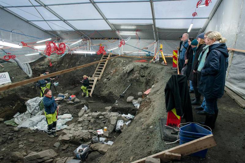 Z Ei gruppe på ti personar frå byantikvaren i Trondheim var på omvisning ved utgravingane tysdag ­denne veka. Alle ser ned på arkeolog Anna Petersén, som forklarar funna.