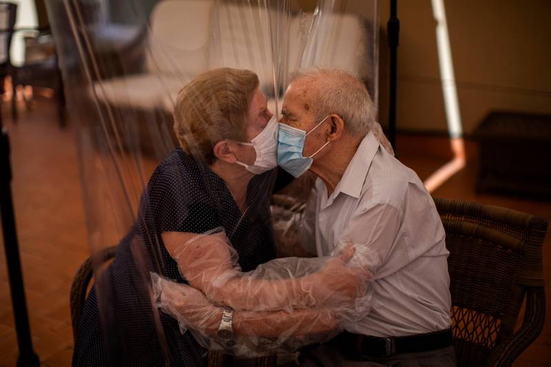 Agustina Cañamero, 81, and Pascual Pérez, 84, hug and kiss through a plastic film screen to avoid contracting the new coronavirus at a nursing home in Barcelona, Spain, Monday, June 22, 2020. The Ballesol Fabra i Puig elderly care center installed the screens to resume relatives' visits to residents 102 days after a strict, nationwide lockdown separated them. As she and her husband broke out into tears while kissing through layers of protective masks and the transparent plastic film, Cañamero said that the couple had never spent such long time with no physical contact in 59 years of marriage. Nursing homes in Spain have been particularly hit by the novel virus, which has claimed at least 28,300 lives nationwide. (AP Photo/Emilio Morenatti)