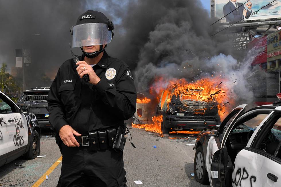 Los Angeles Police Department commander Cory Palka stands among several destroyed police cars as one explodes while on fire during a protest over the death of George Floyd, Saturday, May 30, 2020, in Los Angeles. Floyd died in police custody on Memorial Day in Minneapolis. (AP Photo/Mark J. Terrill)