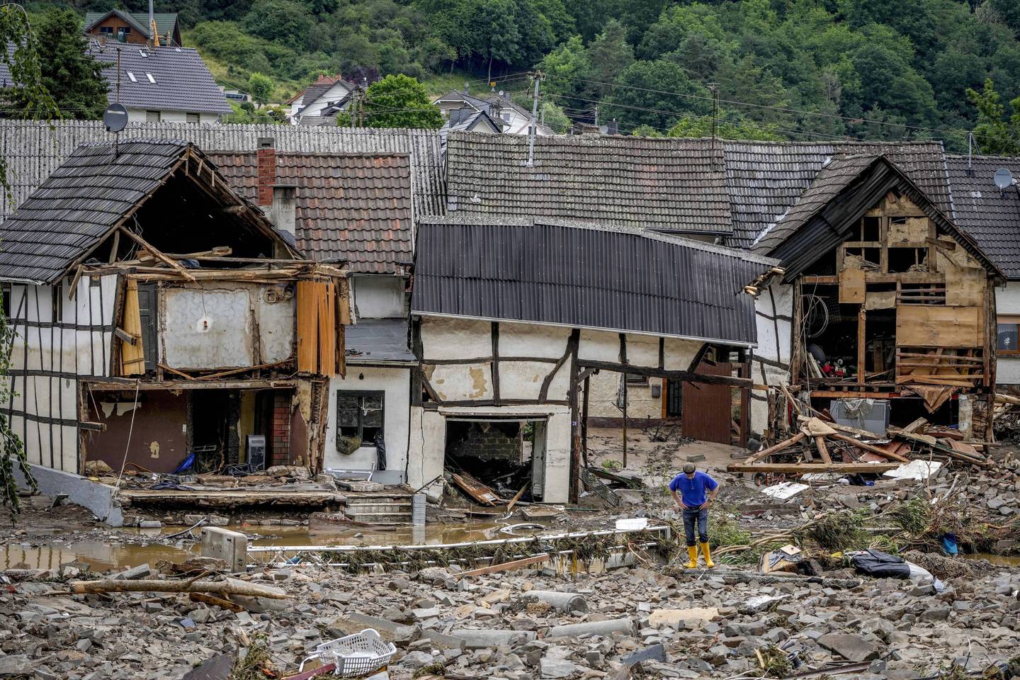 En mann står foran sitt ødelagte hus i Schuld i Ahrdalen 15. juli 2021. Foto: Michael Probst / AP / NTB