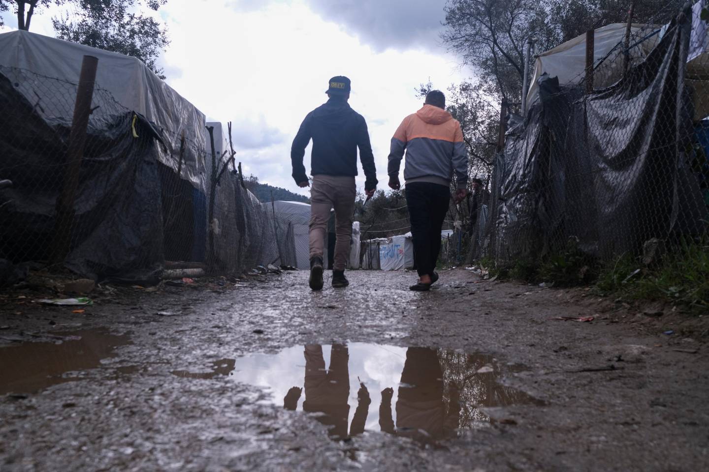 Migrants walk past makeshift tents outside the perimeter of the overcrowded Moria refugee camp on the northeastern Aegean island of Lesbos, Greece, Wednesday, March 11, 2020. Camps on Lesbos and other islands of the eastern Aegean are already overcrowded and operating above their capacity. (AP Photo/Aggelos Barai)