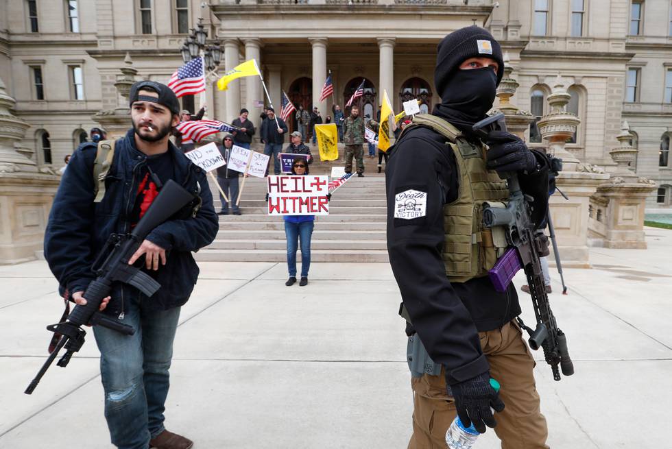 FILE - In this April 15, 2020, file photo protesters carry rifles near the steps of the Michigan State Capitol building in Lansing, Mich. Protesters drove past the Michigan Capitol to show their displeasure with Gov. Gretchen Whitmer's orders to keep people at home and businesses locked during the new coronavirus COVID-19 outbreak. (AP Photo/Paul Sancya, File)