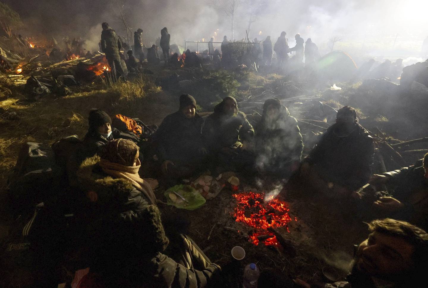 FILE - Migrants warm themselves near a fire at the checkpoint "Kuznitsa" at the Belarus-Poland border near Grodno, Belarus, on Nov. 16, 2021. The U.N. migration agency says the coronavirus pandemic has “radically altered” mobility around the world, projecting in a new report that the growth in the number of international migrants is likely to remain weaker as long as travel and other restrictions remain. (Maxim Guchek/BelTA via AP)