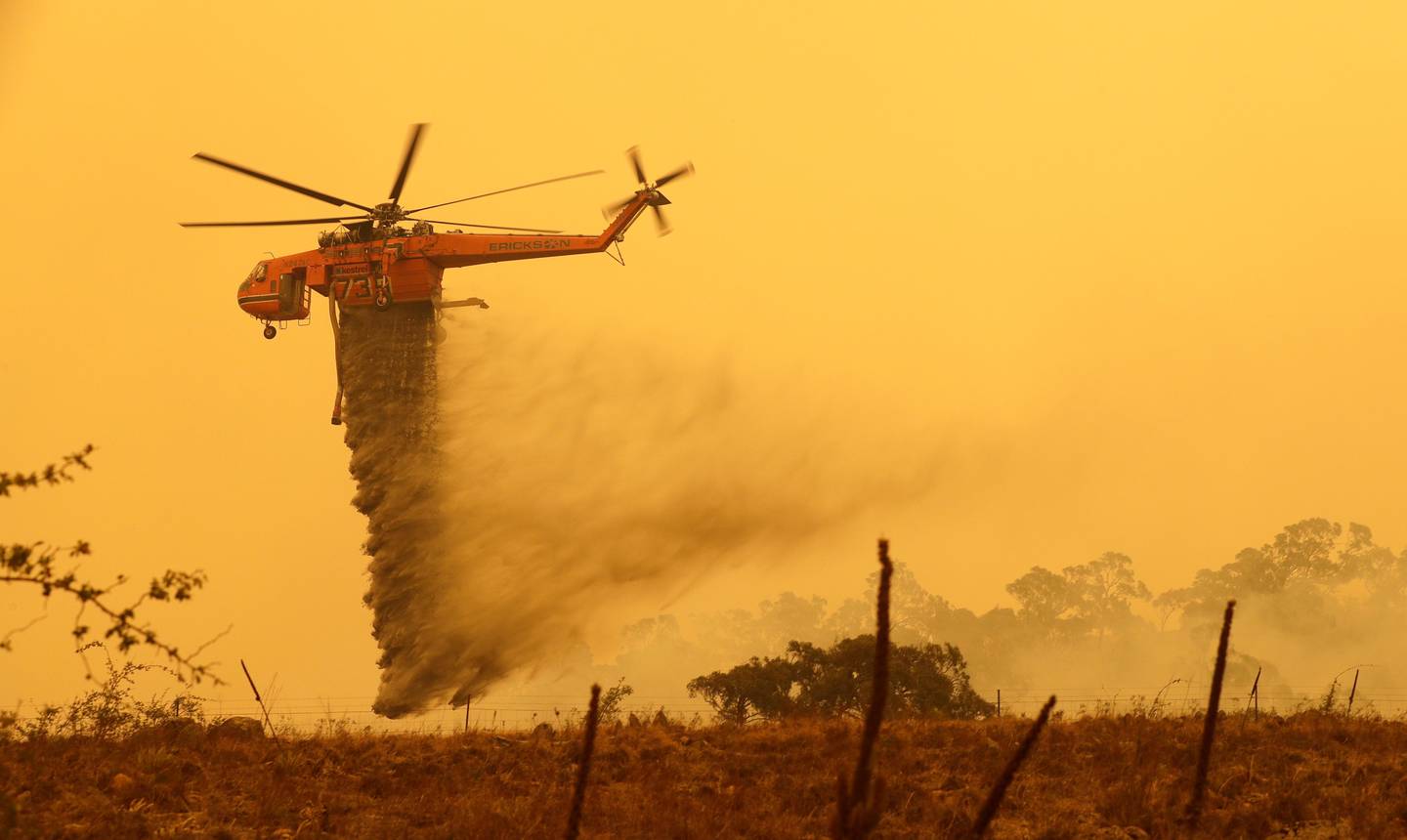 A helicopter drops water on a fire near Bumbalong, south of the Australian capital, Canberra, Saturday, Feb. 1, 2020. The threat is posed by a blaze on Canberra's southern fringe that has razed more than 21,500 hectares (53,000 acres) since it was sparked by heat from a military helicopter landing light on Monday, the Emergency Services Agency said. (AP Photo/Rick Rycroft)