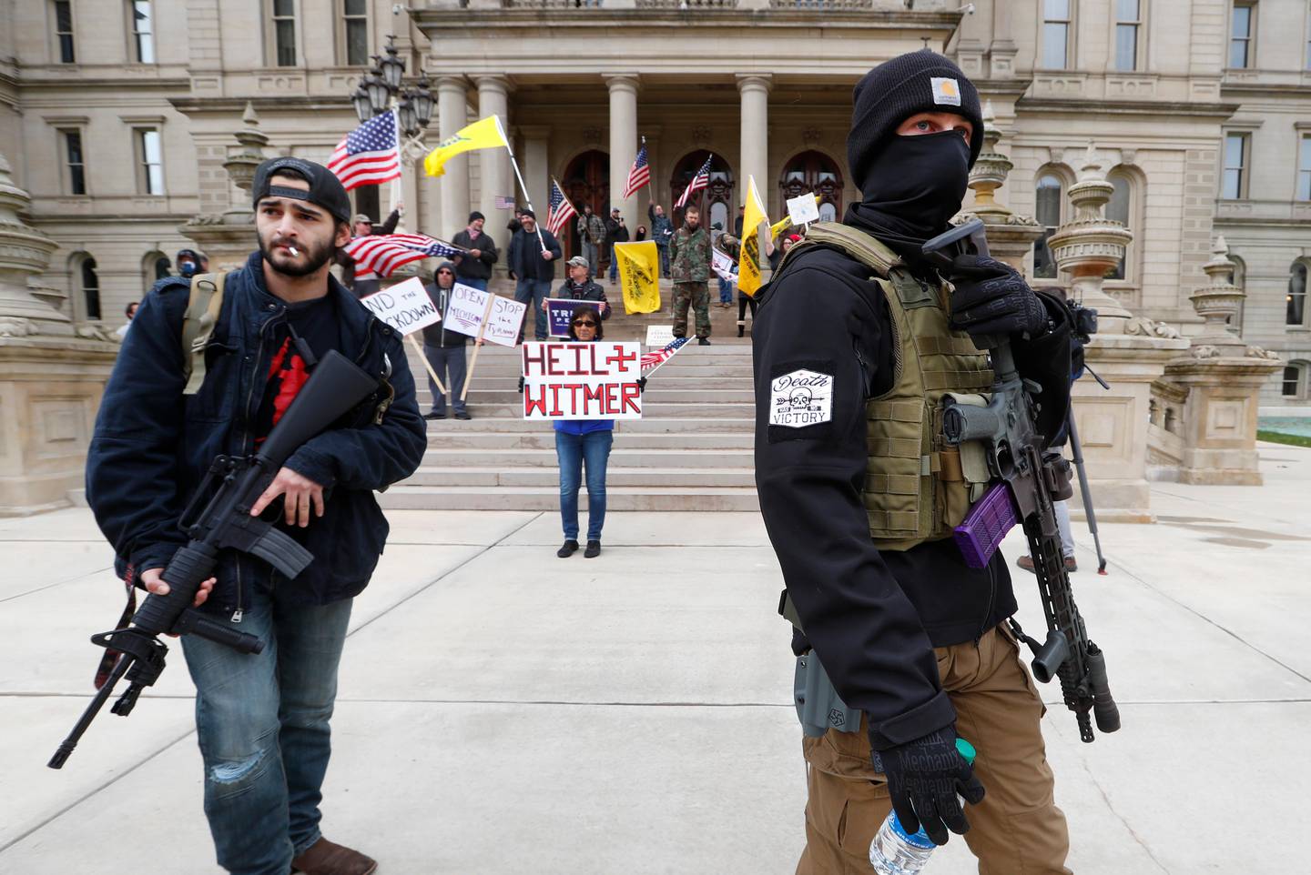 FILE - In this April 15, 2020, file photo, protesters carry rifles near the steps of the Michigan State Capitol building in Lansing, Mich. Many African Americans watching protests calling for easing restrictions meant to slow the spread of the new coronavirus see them as one more example of how their health and their rights just dont seem to matter. (AP Photo/Paul Sancya, File)