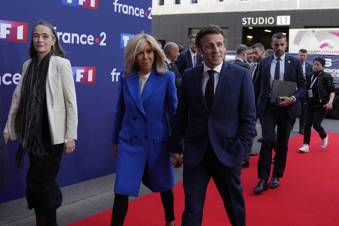 Centrist candidate and French President Emmanuel Macron and his wife Brigitte Macron arrive at a television recording studio for a debate with far-right leader Marine Le Pen, Wednesday, April 20, 2022 in La Plaine-Saint-Denis, outside Paris. In the climax of France's presidential campaign, centrist President Emmanuel Macron and far-right contender Marine Le Pen meet in a one-on-one television debate that could prove decisive before Sunday's runoff vote. At left is chief executive officer of French TV Group France Televisions Delphine Ernotte. (AP Photo/Francois Mori)