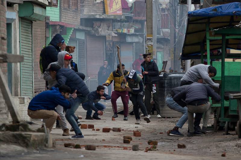 Kashmiri protesters run for cover as they during clash with Indian police men in Srinagar, Indian controlled Kashmir, Tuesday, Feb. 26, 2019. Indian forces in Indian portion of Kashmir used tear gas shells to quell protests against raids on key separatist leaders by Indian intelligence officers. (AP Photo/ Dar Yasin)