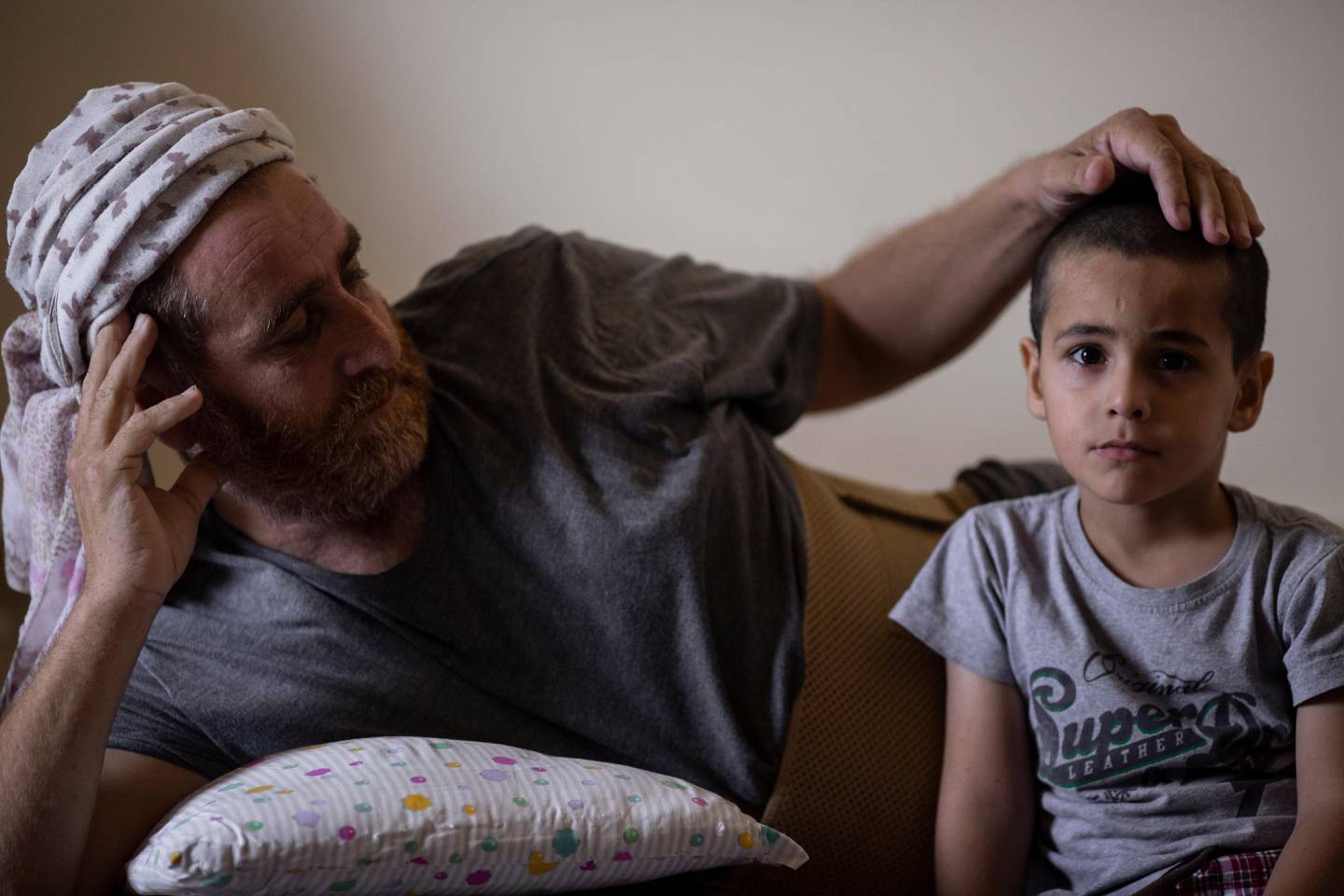Ali Kinno comforts his son Ahmad at a temporary apartment in the coastal town of Jiyeh, south of Beirut, Lebanon, Tuesday, Sept. 15, 2020. The Kinno family from Syria's Aleppo region was devastated in the wake of the Aug. 4 explosion at the Beirut port -- Hoda, 11, suffered a broken neck and other injuries and her sister Sidra, 15, died in the explosion. (AP Photo/Hassan Ammar)