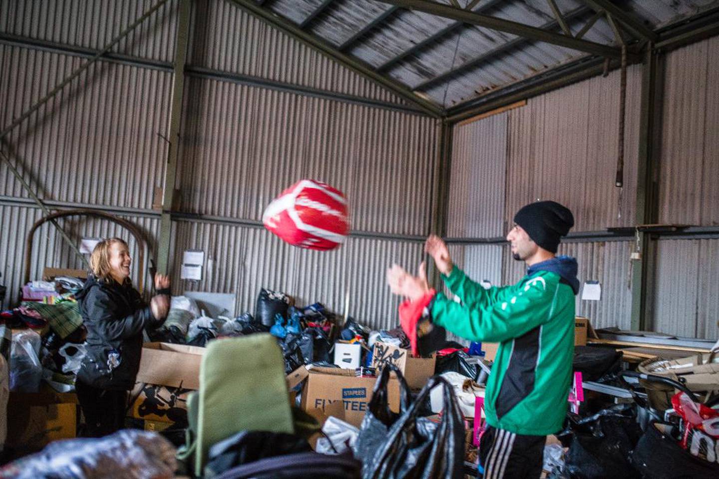 Syriske Mouhammed Hussien kaster en pose med klær til tyske Anja Franke. Hussien er nylig ankommet syrisk flyktning og frivillig i RWTN. Sammen med landsmannen Diab Alhlh er han en av Eva-Lotta Sandbergs viktigste støttespillere.