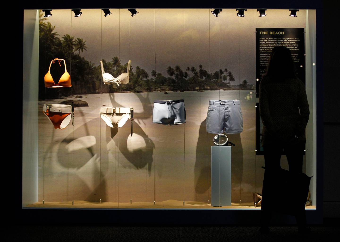 A visitor looks at a display showing, from left, an orange bikini worn by Jinx, by actress Halle Berry, in the film 'Die Another Day', a white bikini worn by Honey Ryder by actress Ursula Andress in film Dr No, James Bond's, actor Daniel Craig swimming trunk in film 'Casino Royale' and James Bond's, actor Sean Connery beach shorts in the film 'Thunderball' in the exhibition 'Designing 007 - Fifty Years of Bond Style' at the Barbican centre in London, Thursday, July 5, 2012. (AP Photo/Sang Tan)
