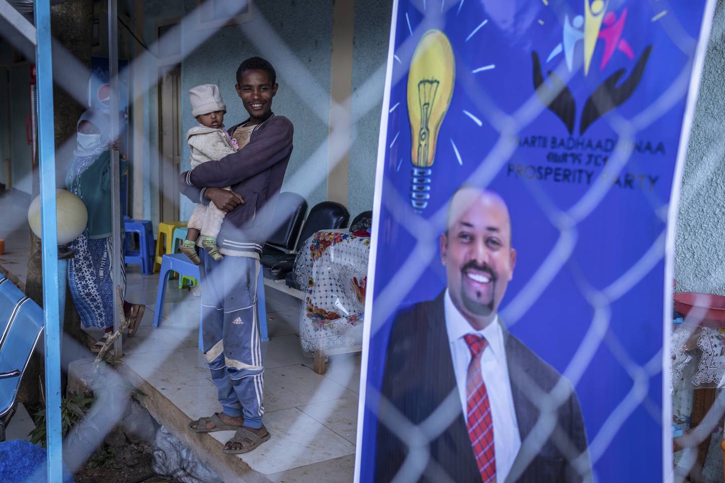 20 år gamle Gezale Abamecha, som har datteren på armen, står ved siden av en valgplakat der Etiopias statsminister Abiy Ahmed ber om fornyet tillit fra velgerne. Mandag holdes det valg på ny nasjonalforsamling i Etiopia, men millioner får ikke delta. Foto: AP / NTB  