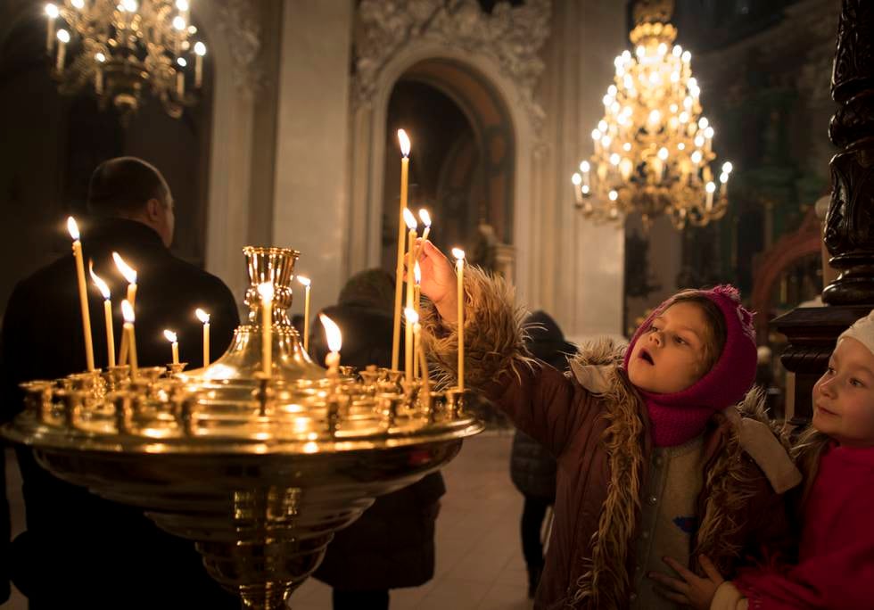 A child lights a candle, during the liturgy on Orthodox Christmas Eve in the Prechistensky, the Cathedral Palace in Vilnius, Lithuania, Friday, Jan. 6, 2017. (AP Photo/Mindaugas Kulbis)