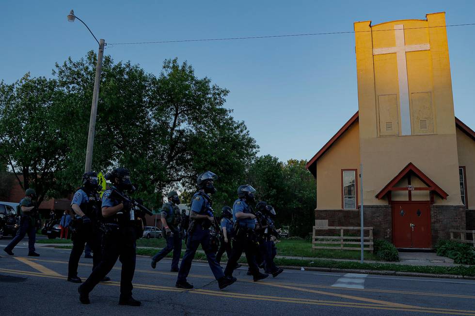 FILE - St. Paul Police officers move in on a crowd past a church, Thursday, May 28, 2020, in St. Paul, Minn.  The Rev. Charles Graham and other Twin Cities faith leaders who minister to communities historically ravaged by racial injustice know their neighborhoods are also the most vulnerable to poverty and crime. Most of the worst looting and vandalism this week struck long-established Native and African American areas that more recently became home to large groups of Hmong, Somali and Latino migrants.(AP Photo/Julio Cortez)