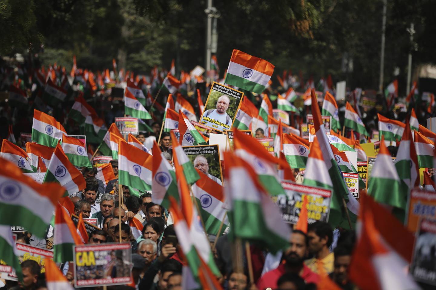 Supporters of a contentious new citizenship law wave Indian national flags as they participate in a protest demonstration organized by Hindu organizations in New Delhi that in New Delhi, India, Saturday, Feb. 29, 2020. The law fast-tracks naturalization for some religious minorities from neighboring countries but not Muslims. Opponents say it violates India's secular constitution, and further marginalizes the 200 million Muslims in this Hindu-majority nation of 1.4 billion people. On the eve of U.S.