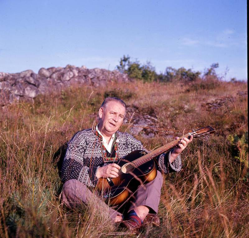 Alf Prøysen fotografert i 1964 med steinrøys i bakgrunnen. Da visesangeren og forfatteren ble født for 102 år siden var det Jordmor-Helga som tok imot ham.