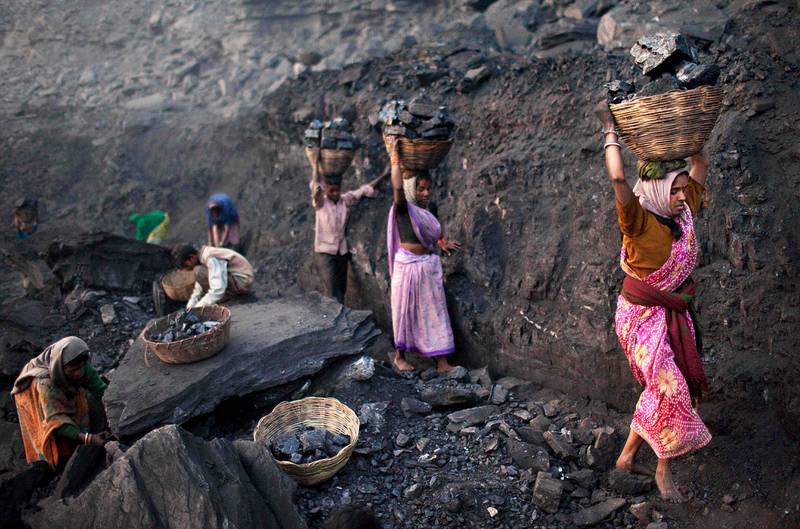 FILE - In this Jan. 7, 2011 file photo, people carry baskets of coal scavenged illegally at an open-cast mine in the village of Bokapahari in the eastern Indian state of Jharkhand. The global fleet of coal-fired power plants is projected to begin shrinking by 2022 as plant retirements outpace new construction, according to a new report that warns the heavily-polluting fuel's decline may not come quickly enough to meet international emission reduction goals. (AP Photo/Kevin Frayer, File)