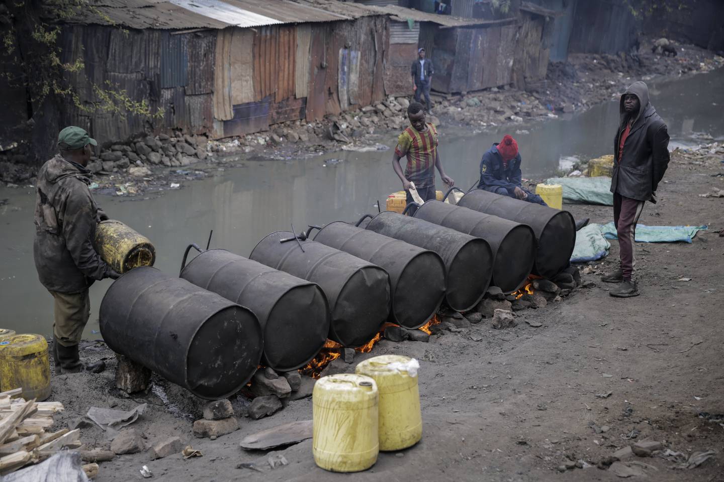 En gruppe menn fører tilsyn med oljefat som inneholder et hjemmebrygget brennevin, lokalt kjent som «chang'aa». De holder til i fattigstrøket Mathare i Nairobi. Presidentvalget 9. august har rippet opp i landets problemer med sosial ulikhet og korrupsjon. Mange frykter derfor et urolig valg. Foto: Brian Inganga / AP / NTB