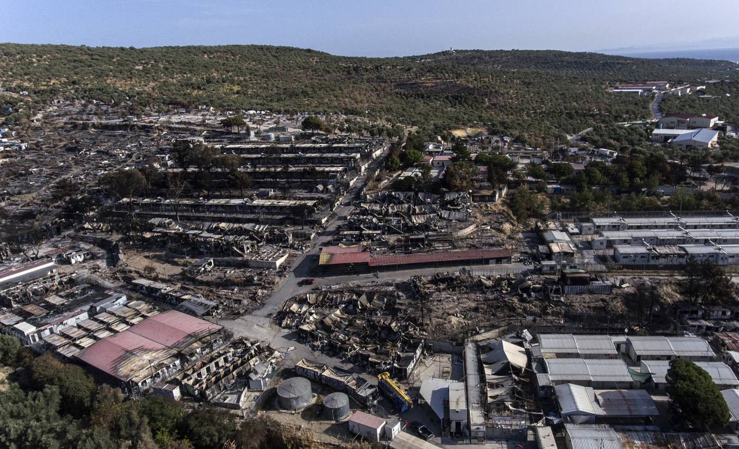 The burned Moria refugee camp is seen from above on the northeastern island of Lesbos, Greece, Monday, Sept. 28, 2020. About 700 people will leave later today from Lesbos for mainland Greece, twenty days after successive fires that started before dawn on Sept. 9, devastating the Moria refugee camp and making more than 12,000 inhabitants homeless during a COVD-19 lockdown. (AP Photo/Panagiotis Balaskas)