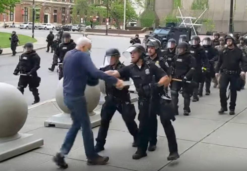 In this image from video provided by WBFO, a Buffalo police officer appears to shove a man who walked up to police Thursday, June 4, 2020, in Buffalo, N.Y. Video from WBFO shows the man appearing to hit his head on the pavement, with blood leaking out as officers walk past to clear Niagara Square. Buffalo police initially said in a statement that a person was injured when he tripped & fell, WIVB-TV reported, but Capt. Jeff Rinaldo later told the TV station that an internal affairs investigation was opened. Police Commissioner Byron Lockwood suspended two officers late Thursday, the mayors statement said. (Mike Desmond/WBFO via AP)