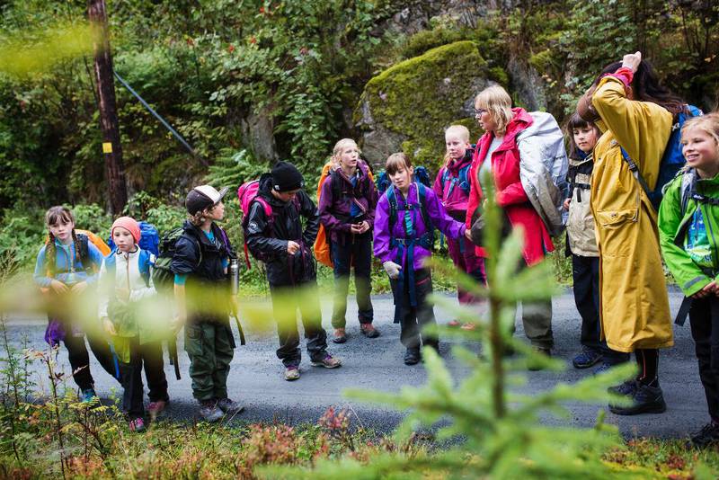 Lærer Helga Brekke og elevene stopper ved stien for å se hvordan regnet har forandret spindelvev i lyngen til små kunstverk.