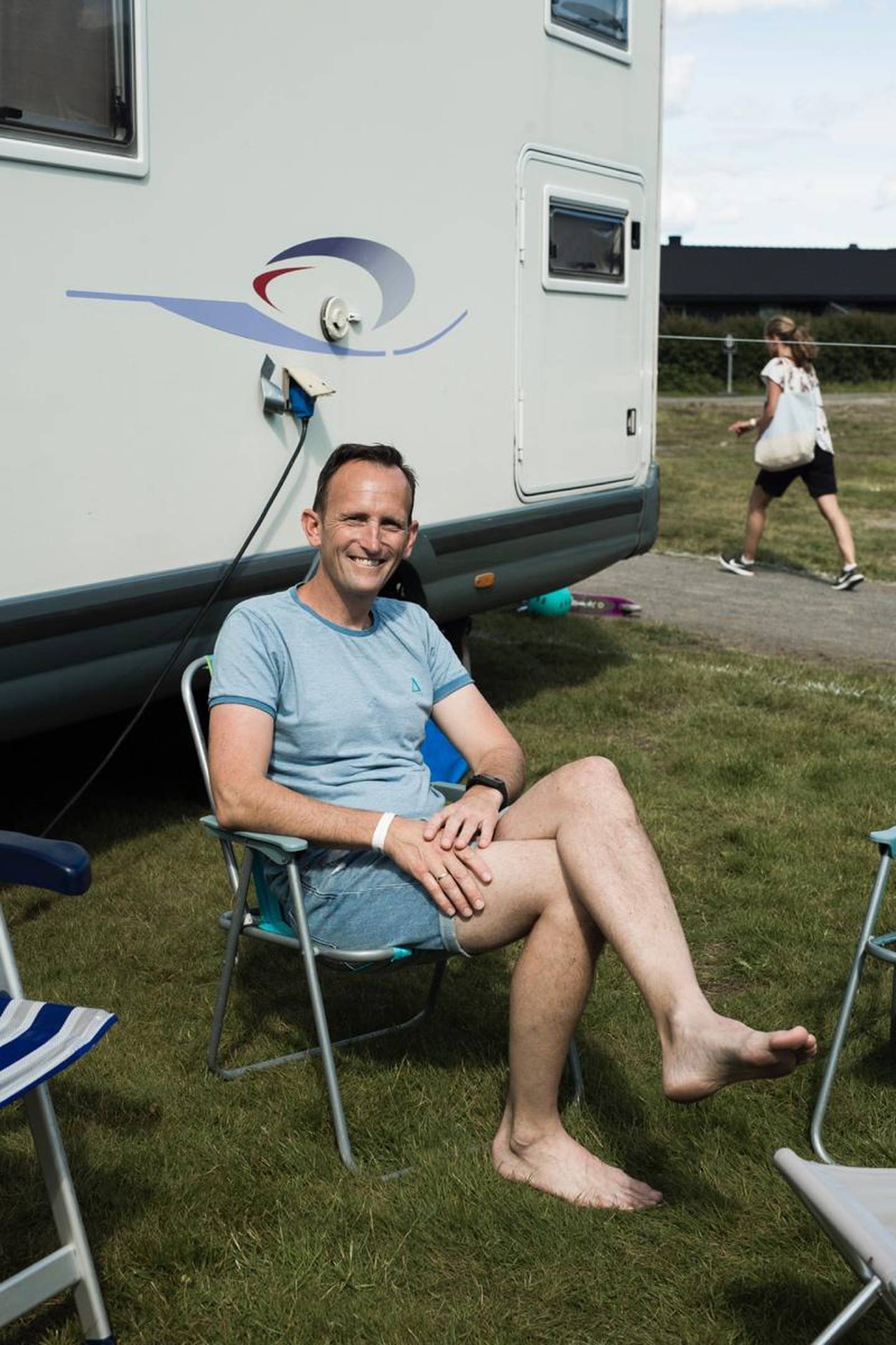 I solsteiken foran en campingvogn sitter Jon Kleiveland sitter sammen med en kamerat.