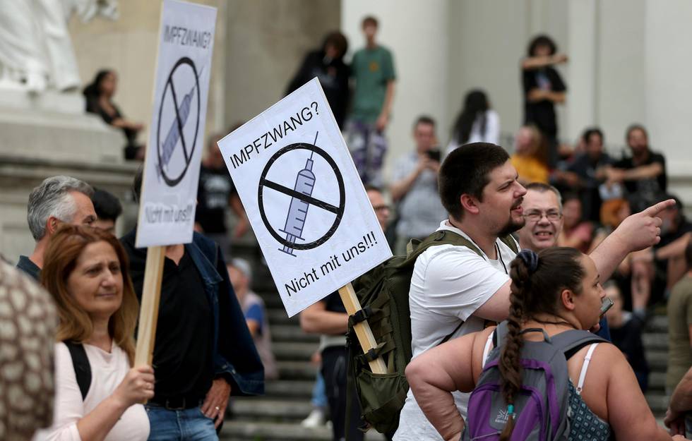 A protester holds a banner that reads "Compulsory vaccination, not with us", as participants obey social distancing rules during a demonstration against COVID-19 measures implemented by the Austrian government in Vienna, Austria, Saturday, Aug. 29, 2020. (AP Photo/Ronald Zak)