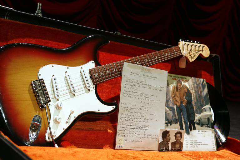 A selection of rock 'n' roll memorabilia from an upcoming Christie's auction sit on display at The Hard Rock Cafe Tuesday, Nov. 21, 2006 in New York.  From left are a 1968 Fender Stratocaster in sunburst finish previously owned by Jimi Hendrix, a page of lyrics in Paul McCartney's hand for "Maxwell's Silver Hammer" from 1968, a Toronto Police Department mugshot of Jimi Hendrix from 1969, and a white label demo copy of "The Freewheelin' Bob Dylan" with handwritten ammendments to the record details in Dylan's hand from 1963.  The items will be sold along with others at an auction at Christie's Dec. 4 in New York.  (AP Photo/Jason DeCrow)