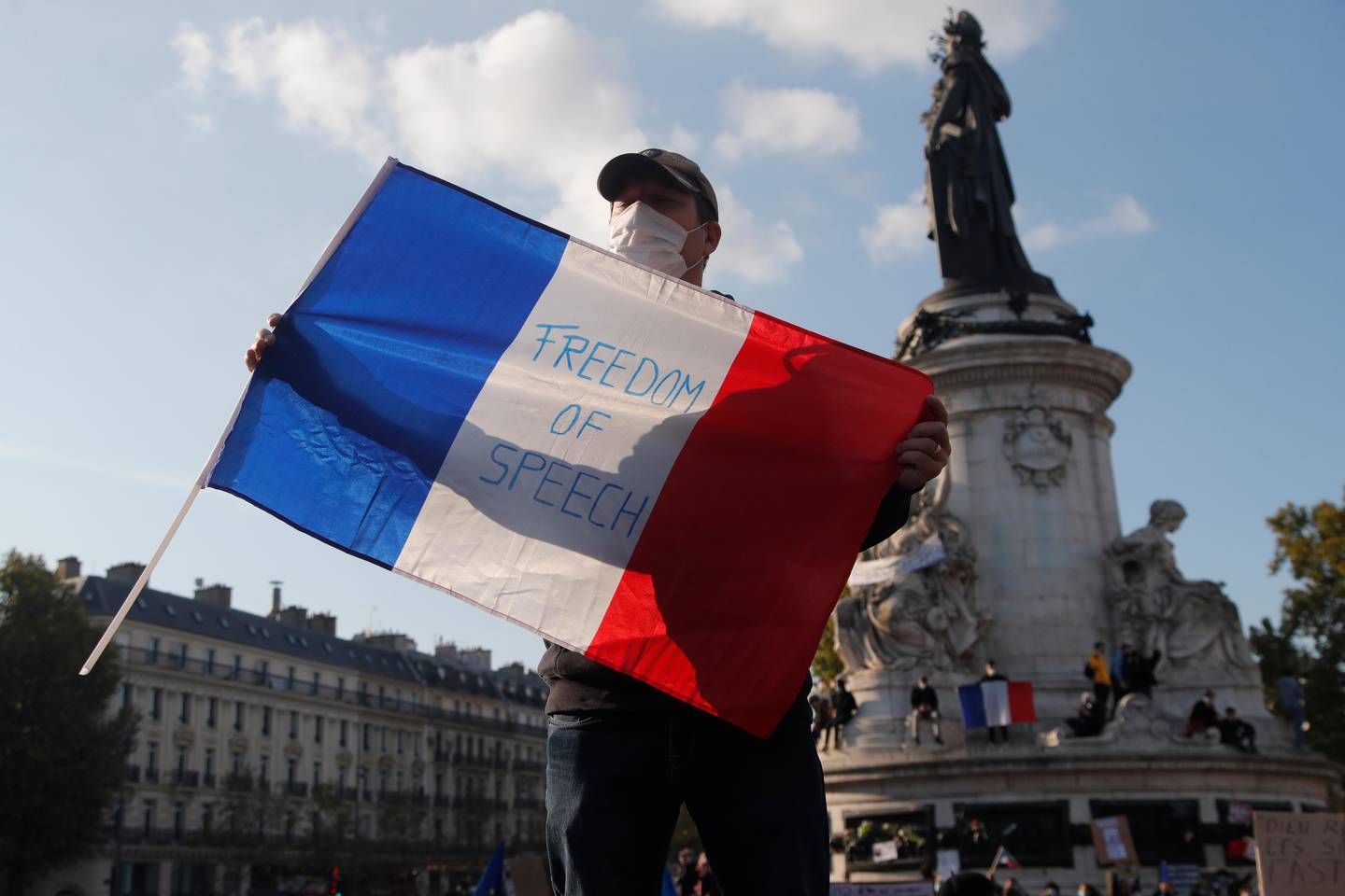 A demonstrator holds a French flag with the slogan "Freedom of Speech" during a demonstration Sunday Oct. 18, 2020 in Paris. Demonstrations around France have been called in support of freedom of speech and to pay tribute to a French history teacher who was beheaded near Paris after discussing caricatures of Islam's Prophet Muhammad with his class. Samuel Paty was beheaded on Friday by a 18-year-old Moscow-born Chechen refugee who was shot dead by police. (AP Photo/Michel Euler)