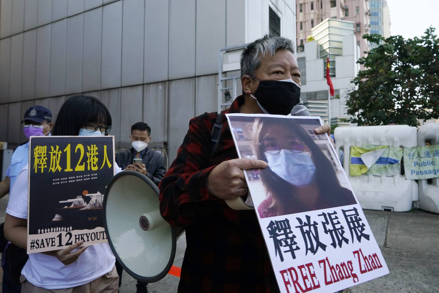 Pro-democracy activists, including Lee Cheuk-Yan, right, hold placards with the picture of Chinese citizen journalist Zhang Zhan as they march to the Chinese central government's liaison office, in Hong Kong, Monday, Dec. 28, 2020. Zhang, a former lawyer and citizen journalist from Shanghai, has been sentenced to four years in prison for her reporting on the initial coronavirus outbreak in Wuhan, China. The activists demanded the releases of Zhang, as well as the 12 Hong Kong activists detained at sea by Chinese authorities. (AP Photo/Kin Cheung)