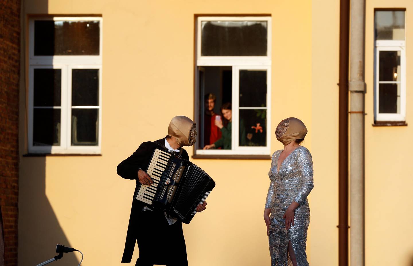 Street musicians entertain residents, as people stay in their houses to counter the spread of coronavirus, in Prague, Czech Republic, Tuesday, April 7, 2020. The Czech Republic's government has incorporated dramatic restrictive measures to try and stem the spread of the new coronavirus called COVID-19. The new coronavirus causes mild or moderate symptoms for most people, but for some, especially older adults and people with existing health problems, it can cause more severe illness or death. (AP Photo/Petr David Josek)
