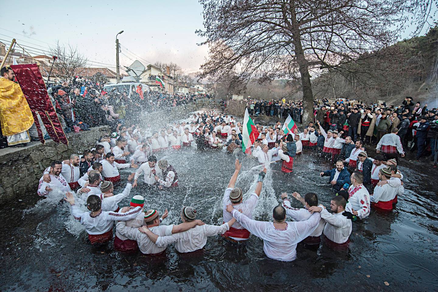 Bulgarians sing and chain dance in the icy waters of the Tundzha river during Epiphany, in Kalofer, Bulgaria, Monday, Jan. 6, 2020. Thousands of Orthodox Christian worshippers plunged into the icy waters of rivers and lakes across Bulgaria on Monday to retrieve crucifixes tossed by priests in ceremonies commemorating the baptism of Jesus Christ. In the mountain city of Kalofer, in central Bulgaria, dozens of men dressed in white embroidered shirts waded into the frigid Tundzha River waving national flags and singing folk songs. (AP Photo)