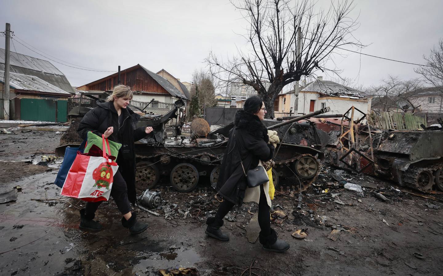 To kvinner passerer en sønderbombet russisk stridsvogn i Bucha, drøyt 30 kilometer nordvest for Kyiv. Foto: AP / NTB