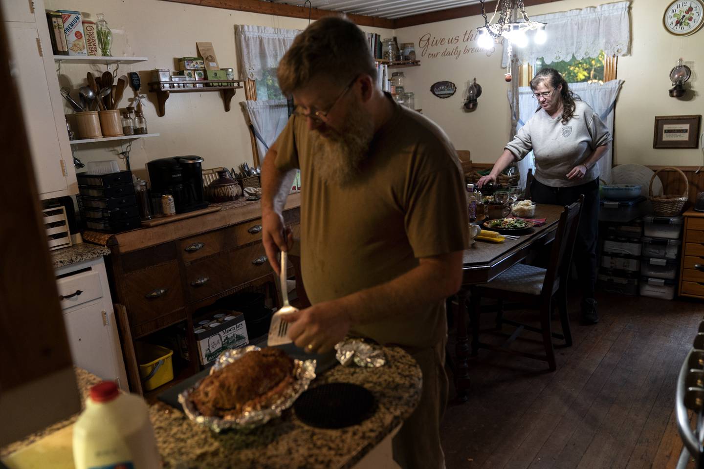Mark Carlson serves up his home-cooked meatloaf for dinner as his wife, Linda, pours a glass of wine at their home in Hammond, Wis., Wednesday, Sept. 28, 2022. Carlson was swept into office earlier this year when insurgent right-wing conservatives created a powerful local voting bloc, energized by fury over COVID lockdowns, vaccination mandates and the unrest that shook the country after George Floyd was murdered by a police officer in Minneapolis, just 45 minutes away. (AP Photo/David Goldman)