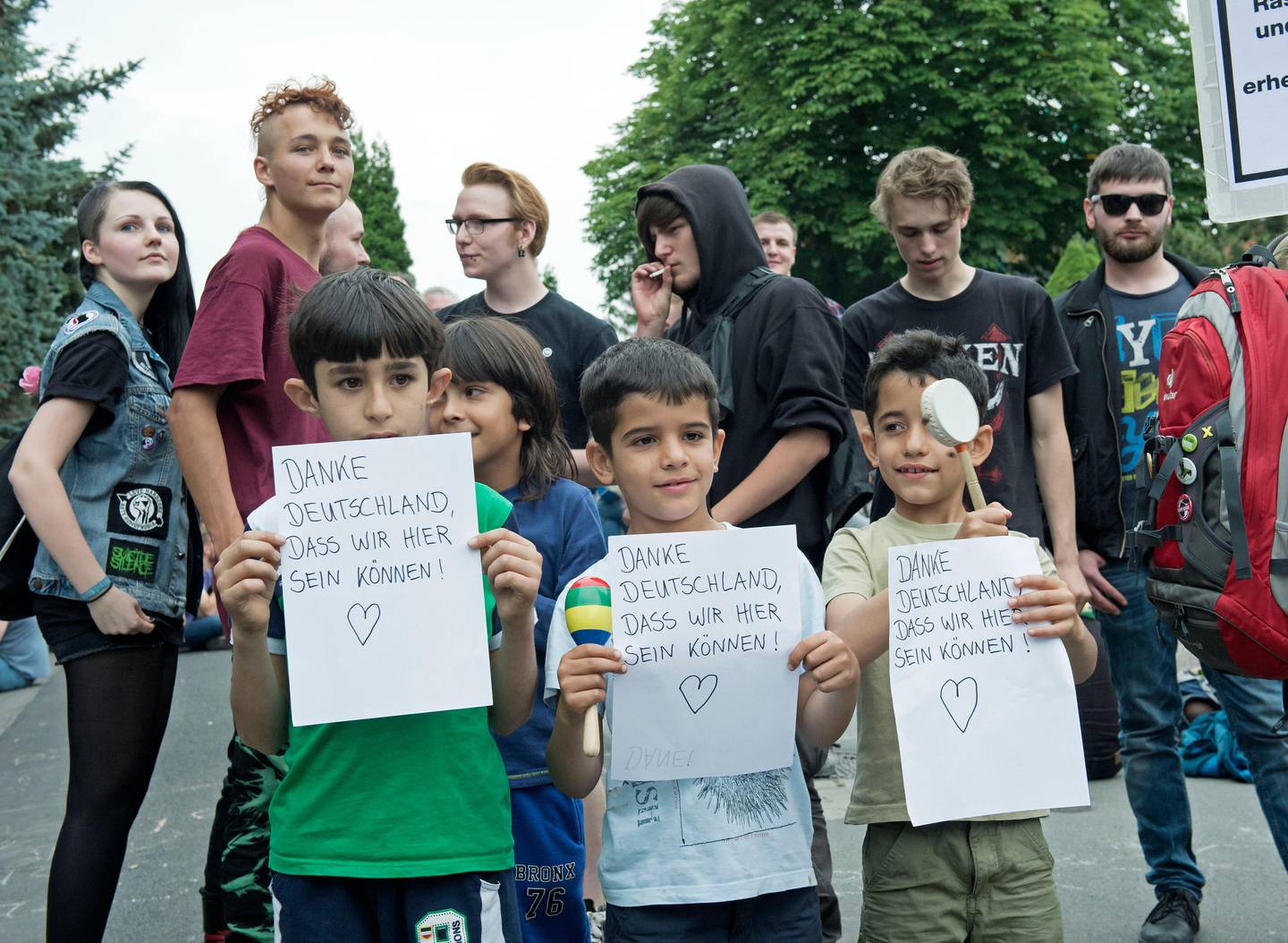 Children of refugees hold pieces of paper in front of the accommodation for immigrants in Freital near Dresden, eastern Germany, Friday, June 26, 2015. The words read: 'Thank you Germany to be here'. Members of Pegida, the right-wing movement that staged regular rallies in Dresden and elsewhere against immigrants and Muslims, helped initiate protests and demonstrated against the arrival of the first refugee families. (AP Photo/Jens Meyer)