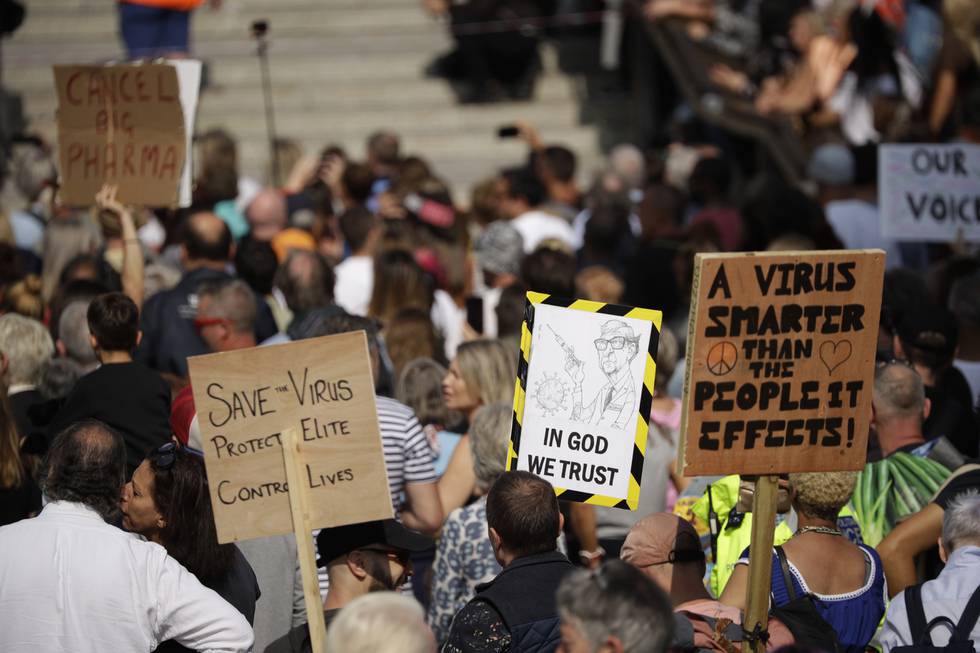 People hold placards including one portraying Bill Gates as they take part in a "Resist and Act for Freedom" protest against a mandatory coronavirus vaccine, wearing masks, social distancing and a second lockdown, in Trafalgar Square, London, Saturday, Sept. 19, 2020. (AP Photo/Matt Dunham)