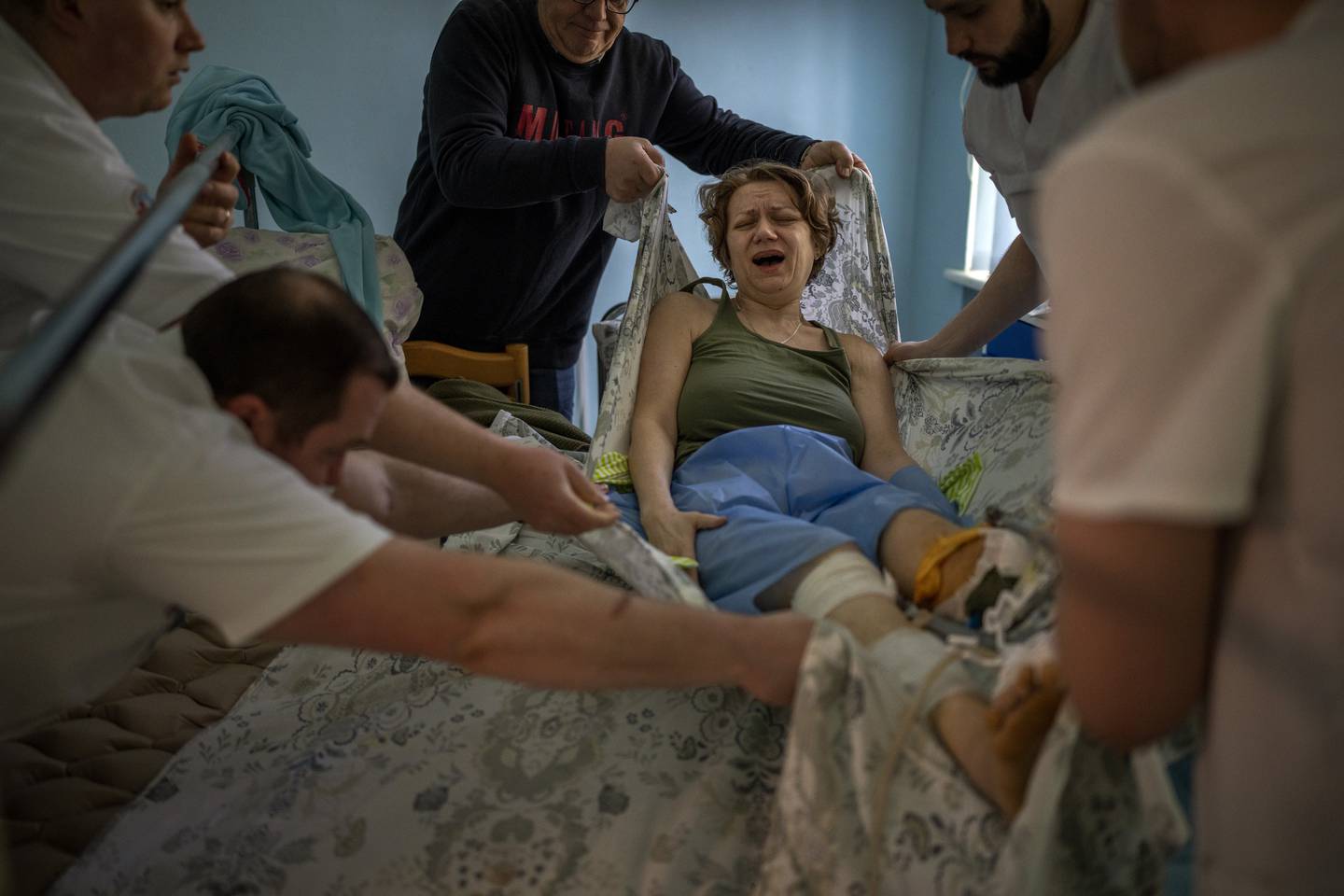 Olena Viter (45) skrik av smerte når ho blir løfta over på ei båre for å gå gjennom ein ny operasjon på eit sjukehus i Kyiv. Olena mista både den 14 år gamle son sin og eit bein i ein eksplosjon i landsbyen Rozvazhiv 14. mars. Foto: Emilio Morenatti / AP / NTB
