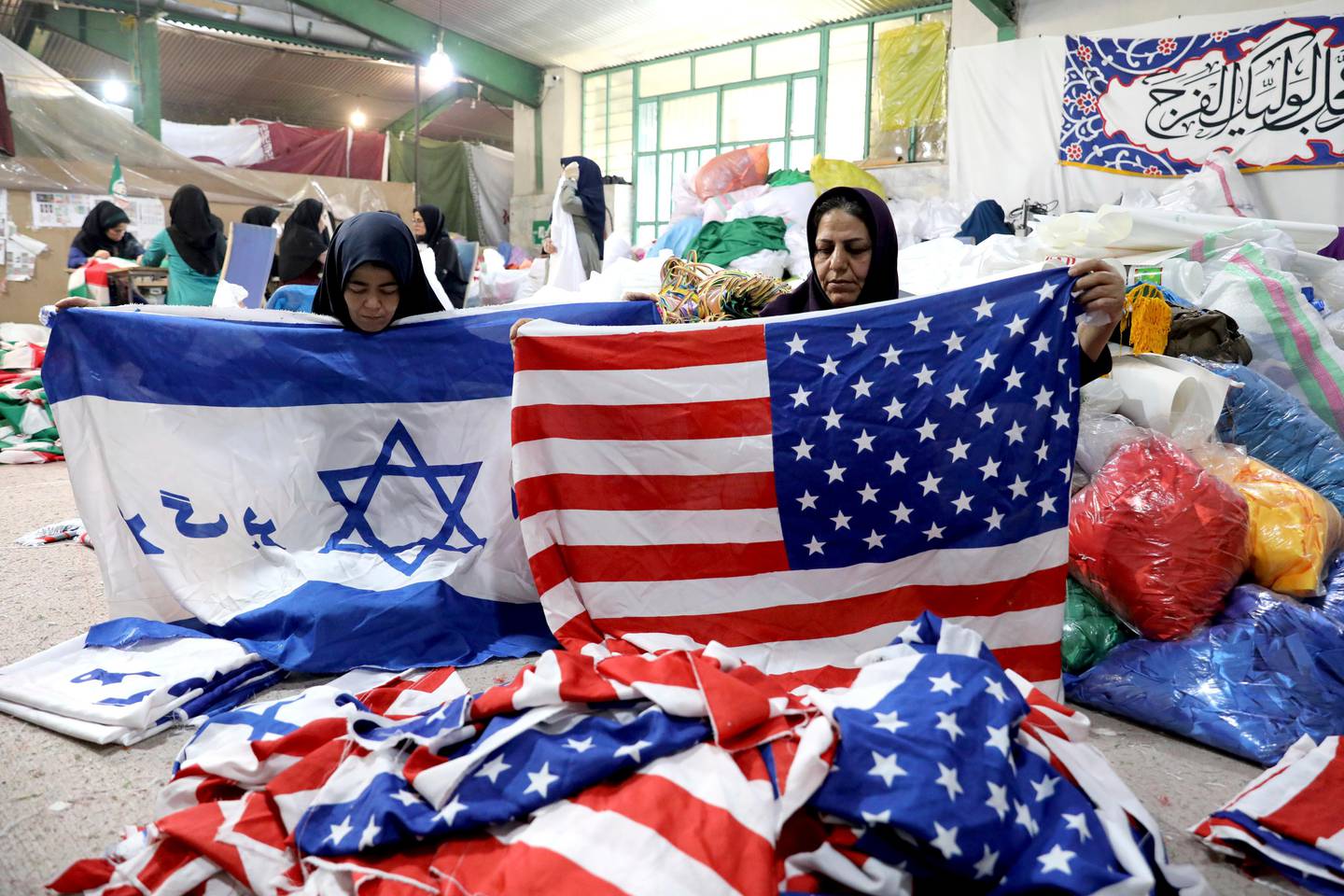 In this Saturday, Feb. 8, 2020 photo, workers fold U.S. flags and Israeli flags with a slogan in Persian which reads, "Death to Israel" at the Diba Parcham Khomein factory in Heshmatieh village, a suburb of Khomein city, in central Iran. Their work is destined to go up in smoke. This factory serves as a major producer for the American and Israeli flags constantly burned at demonstrations in the Islamic Republic. (AP Photo/Ebrahim Noroozi)