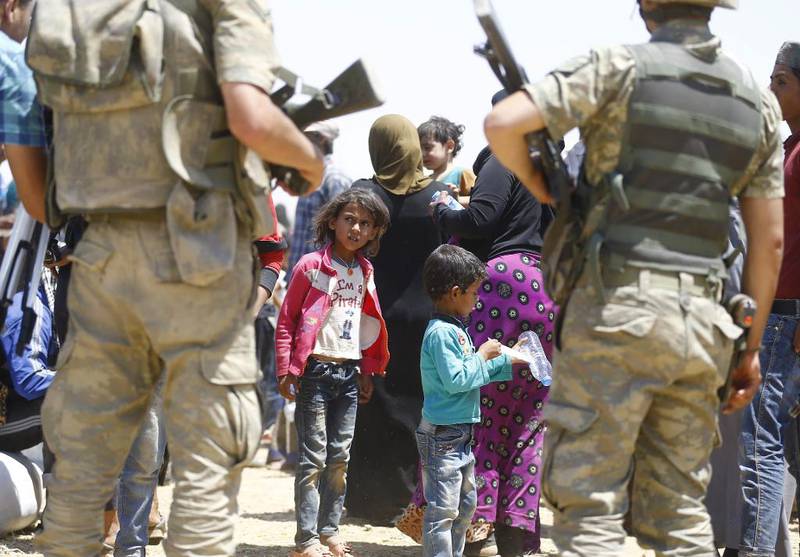 Med tyrkiske soldater rundt seg venter disse syriske jentene på videre transport etter å ha tatt seg inn i Tyrkia.