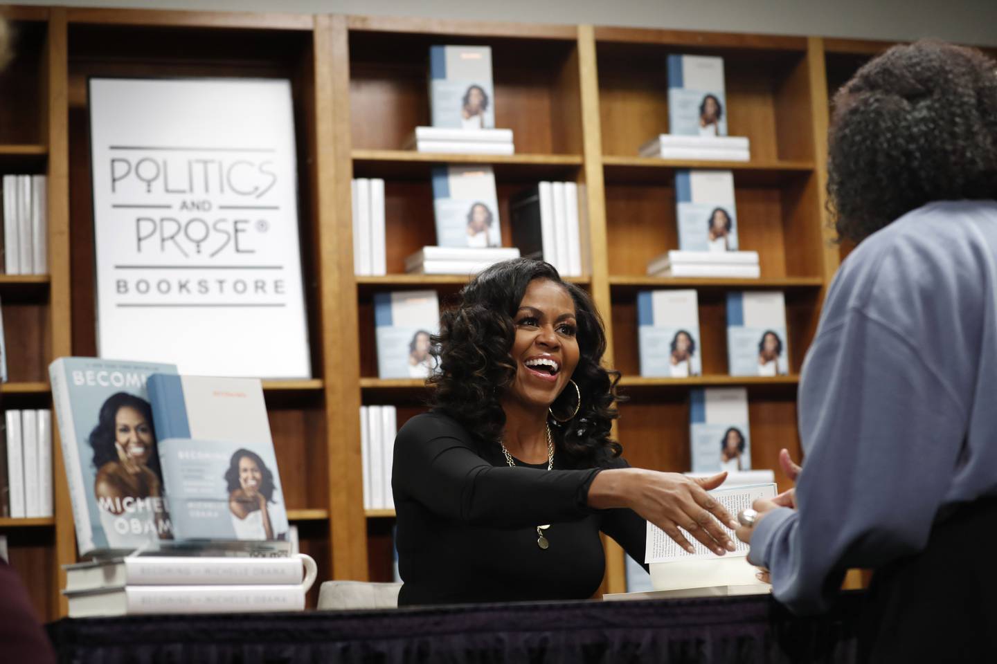 Former first lady Michelle Obama greets people as they buy signed copies of her book, "Becoming," Monday Nov. 18, 2019, at Politics and Prose Bookstore in Washington. (AP Photo/Jacquelyn Martin)