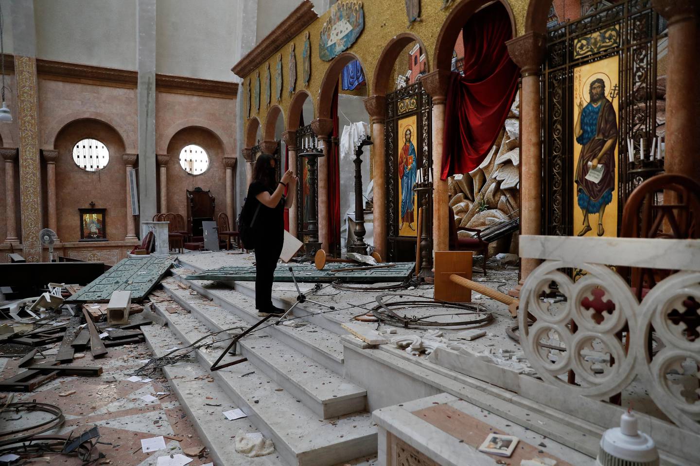A woman takes pictures ofr a damaged church a day after an explosion hit the seaport of Beirut, Lebanon, Wednesday, Aug. 5, 2020. Residents of Beirut awoke to a scene of utter devastation on Wednesday, a day after a massive explosion at the port sent shock waves across the Lebanese capital, killing at least 100 people and wounding thousands. (AP Photo/Hussein Malla)